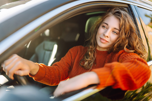 Beautiful woman sitting in car and looking through the window. Car travel, lifestyle, carshering concept.