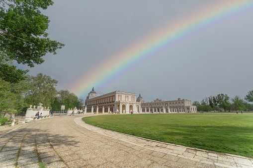 Aranjuez, Spain – September 25, 2021: Gardens of the Royal Palace of Aranjuez with a rainbow crossing the sky. It is a residence of the King of Spain.