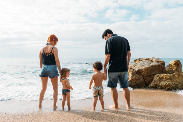 istock Young couple holding kids hands on seashore 1977185563