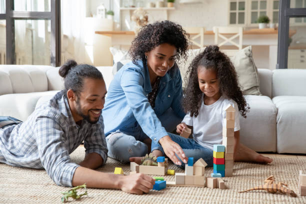 Happy parents and daughter kid playing on heating carpeted floor