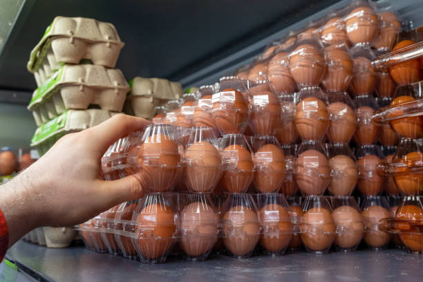 istock Chicken eggs on the store shelf. A customer takes a packaging of chicken eggs from a supermarket fridge. 1977192021