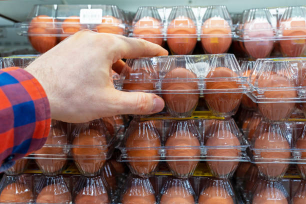 istock Chicken eggs on the store shelf. A customer takes a packaging of chicken eggs from a supermarket fridge. 1977192027