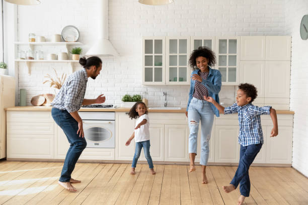 istock Happy joyful couple and sibling kids dancing rock-n-roll in kitchen 1977192039