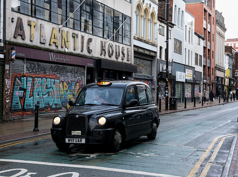 Manchester, United Kingdom - 12 31 2023 : A black English taxi at a standstill, on a street in the Northern Quarter