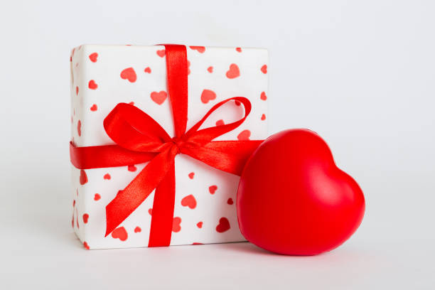 istock gift box with red bow and red heart on colored background. Perspective view. Flat lay 1977193655
