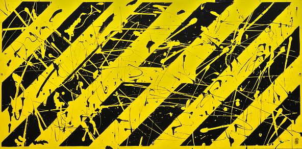 Background composed of black and yellow diagonals, speckled with paint drops.