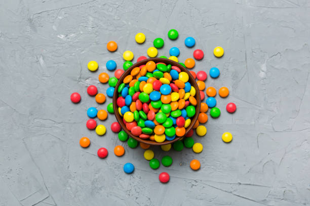 multicolored candies in a bowl on a colored background. birthday and holiday concept. top view with copy space - candy coated zdjęcia i obrazy z banku zdjęć