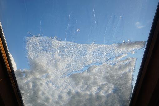 Snow covers this roof window on a sunny day.