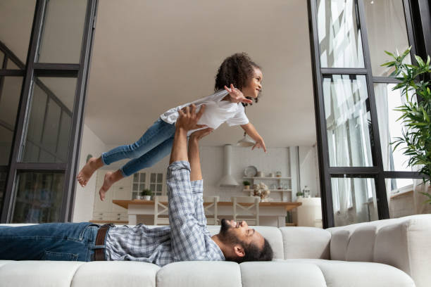 istock Happy father and excited daughter kid playing airplane on couch 1977200193