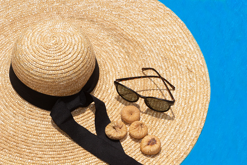 A closeup of a straw hat, sunglasses near the pool