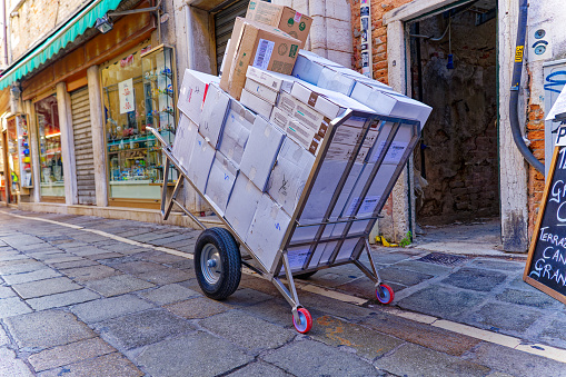 Parked pushcart loaded with white carton boxes at the old town of Italian City of Venice on a sunny summer day. Photo taken August 7th, 2023, Venice, Italy.