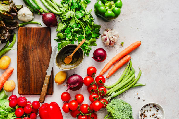 Various vegetables and a wooden cutting board on a table