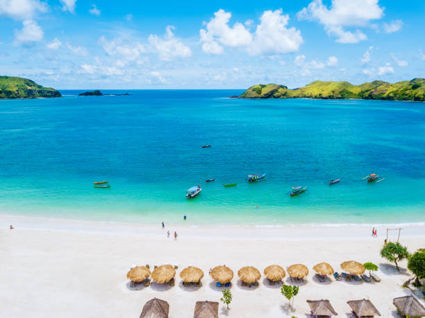 Panoramic View of a Tropical Beach with Crystal Clear Turquoise Water, Lush Green Islands, White Sand, and Blue Sky with Fluffy Clouds. Lombok island.