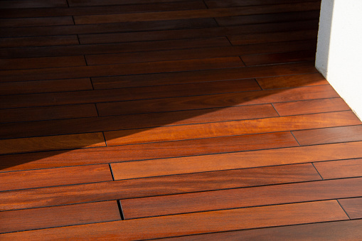 hardwood floor against white wall in sun light and shadow contrast