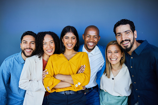 Diverse group of smiling businesspeople standing against a wall in an office