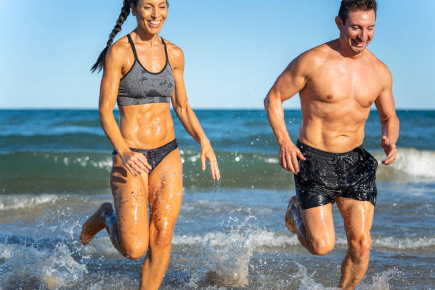 istock Middle aged couple exercising together on the beach this summer 1977320100