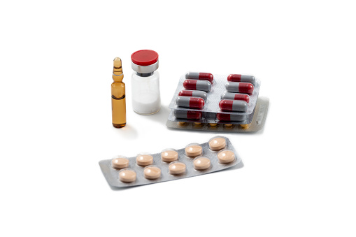 Various injection ampoules and red capsules packed in gray glossy packaging, isolated on white background.