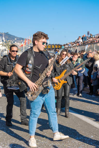 Menton, France-February 12, 2023: Saxophonist playing with a band audience watching on traditional carnival parade of Lemon Festival. International Jazz Day