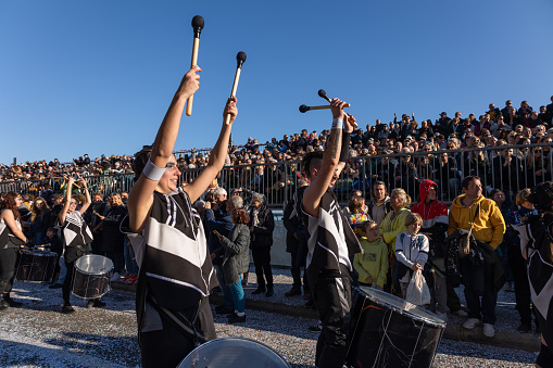 Menton, France-February 12, 2023: Drummers in black and white attire performing audience in the background on traditional carnival parade of Lemon Festival