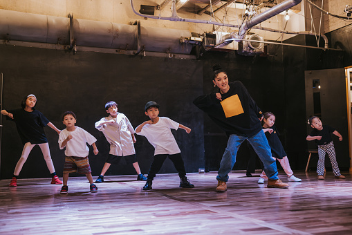 Japanese kids follow their hip hop dance instructor with precision, absorbing the rhythm of the dance moves in a studio