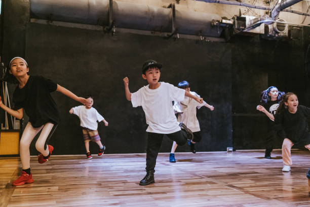 Japanese kids immersed in the rhythm and flow of a hip-hop breakdance class Japanese kids of various ages engage in a hip-hop breakdance session, full of joy and passion for the art form. japanese boy and girl stock pictures, royalty-free photos & images