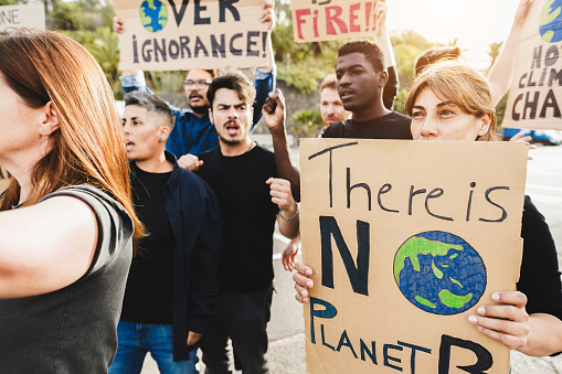 Multigenerational people protest against climate change - Crowd doing demonstration for stopping pollution - Green and environment concept - Focus on right banner