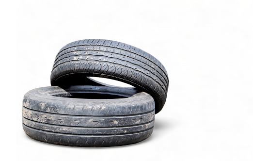 Isolated on a white background two black old car tires with copy space. Reuse of worn out rubber tires. Disposal of used tires. Production of secondary rubber from tires