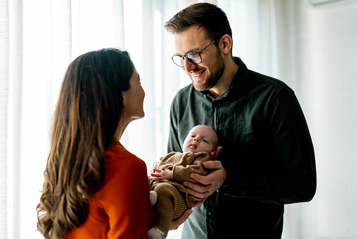 Smiling young parents with their baby girl at home