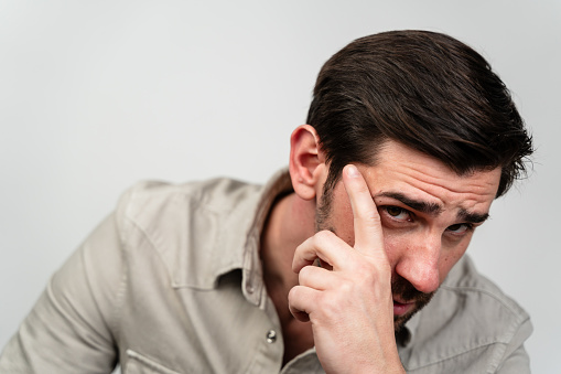 A man holds his hand up to his face, covering his mouth and nose.