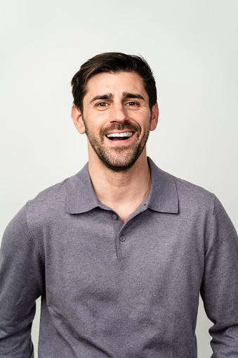 Cheerful male model with a bright smile wearing a casual buttoned shirt.