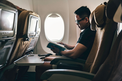 man reading a book on airplane