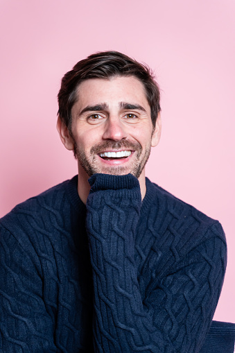 Cheerful man in a blue sweater on a pink background