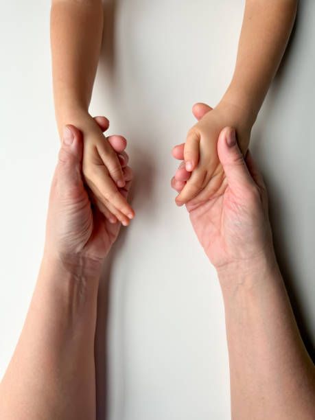 istock Mothers hands holding childs hands on white background. 1977404090