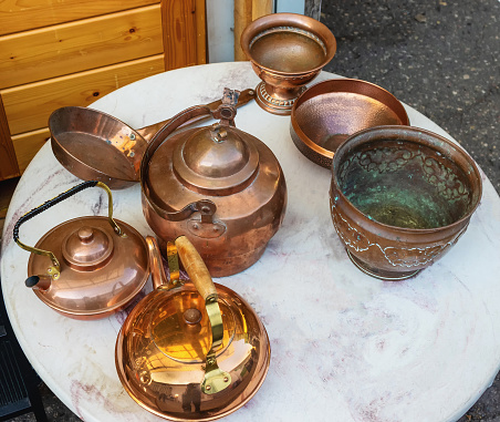 A set of old antique copper utensils on a table in a flea market