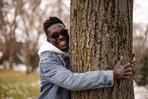 Young man hugging tree at public park