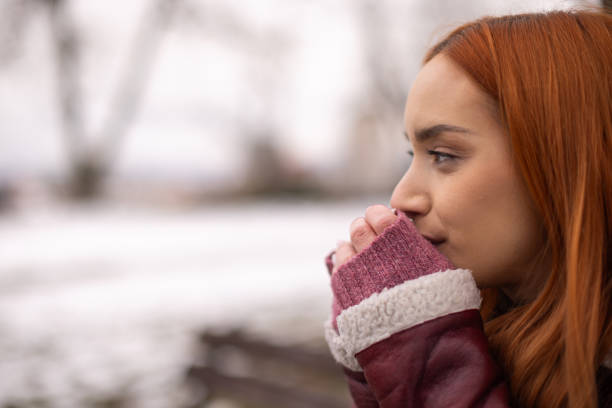 Woman warming up her hands during winter day at public park