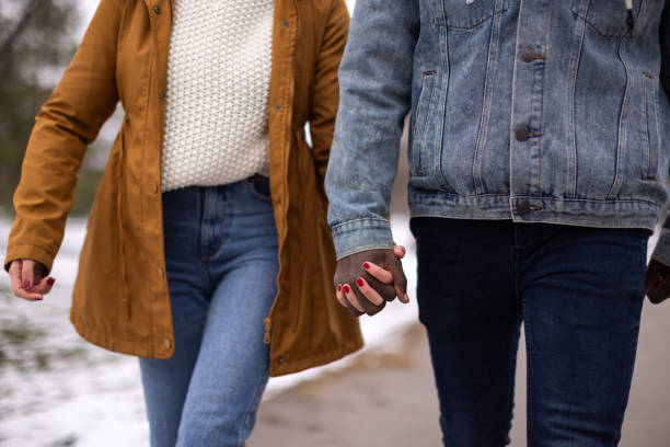 Couple holding hands while walking in public park
