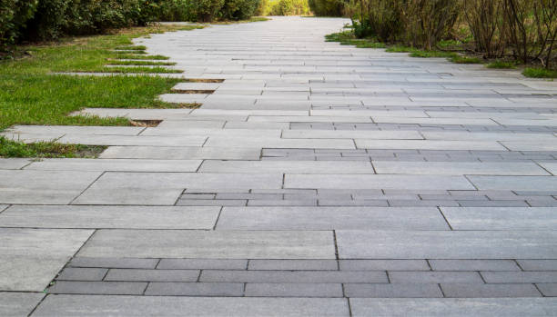 istock Marble path paved with stone and square tiles. The pedestrian path is paved with paving stones. Grass grows between the tiles. Sidewalk in landscape garden design made of tiled stone slabs. No one. 1977419667
