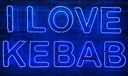 Neon shining sign in blue color on a brick wall with the inscription or slogan I love kebab. Brick wall, background. Bright electric neon light. Cafe-restaurant Doner Kebab
