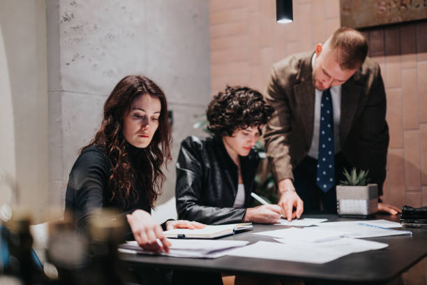 istock Three people, colleagues, engaged in a serious discussion over paperwork in a modern office setting, indicating teamwork and dedication. 1977424127