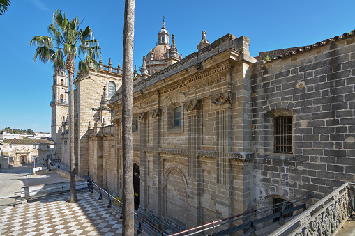 Side view of the beautifully detailed ancient cathedral of Jerez de la Frontera under a clear blue sky.