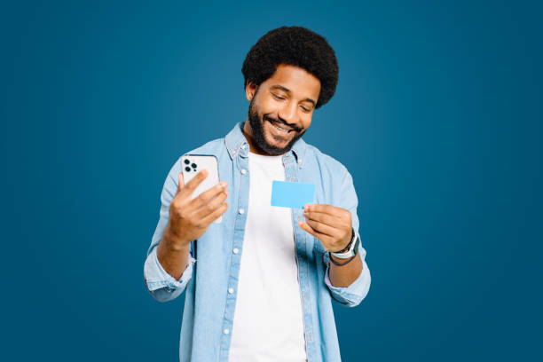 istock The man examines his credit card while holding a smartphone 1977507834