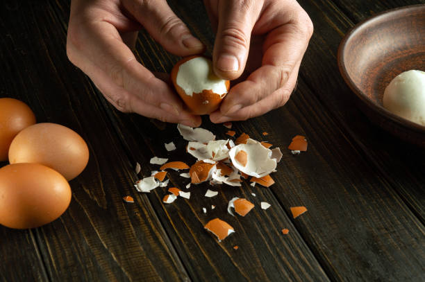 istock Close-up of a man hands peeling a boiled egg on a kitchen black table for a snack 1977516068