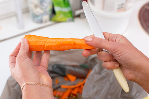 Hands hold peeled carrots and a knife.
