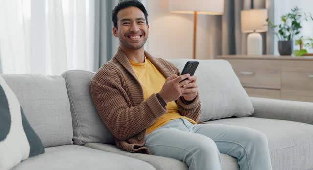 Home cellphone, relax and happy man typing, texting and reading funny email, social media blog and contact web user. Living room couch, mobile smartphone and apartment portrait of networking person
