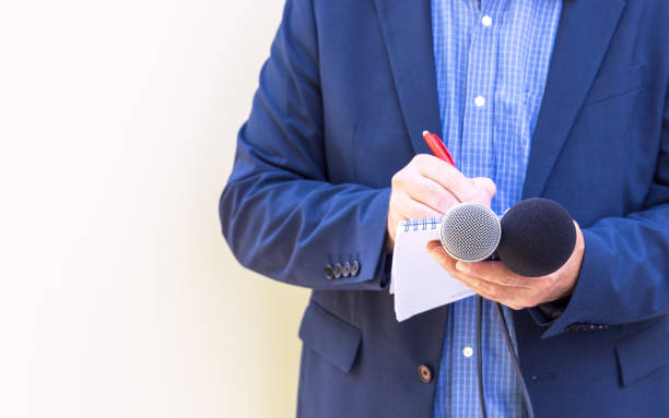 istock Journalist or reporter at media event, holding microphone, writing notes. Journalism concept with copy space. 1977562011
