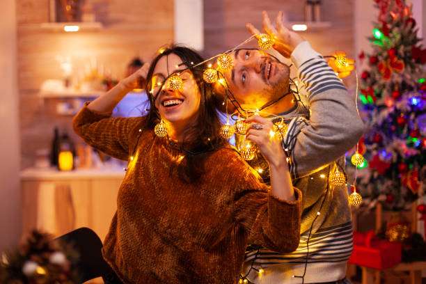 istock Amused couple caughting in christmas tree light during christmastime 1977592108