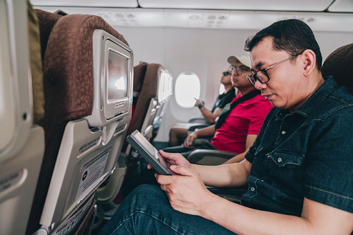 men on airplane using on board entertainment