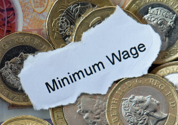 Sterling Bank notes and pound coins. With the words Minimum Wage on a piece of paper London, United Kingdom, January 2, 2024. Scattered sterling currency bank notes and pound coins money. With words Minimum Wage prominently shown on a piece of paper. Studio flat lay close up. minimum wage stock pictures, royalty-free photos & images