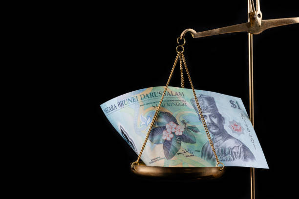 istock Brunei 1 dollar bill on a gold scale 1977633299